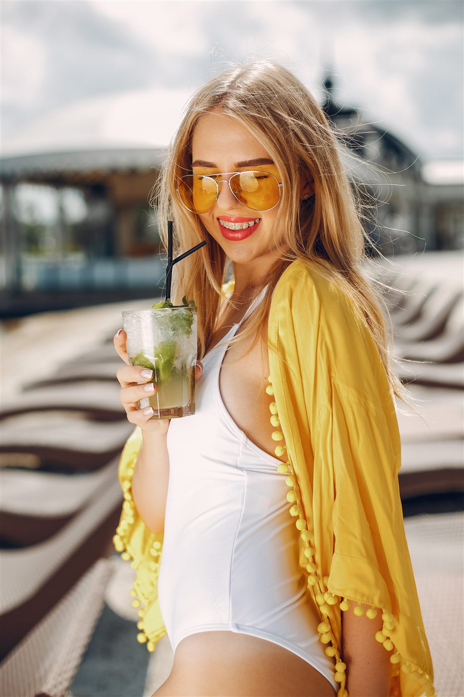 Woman in yellow resort coverup holding a cocktail