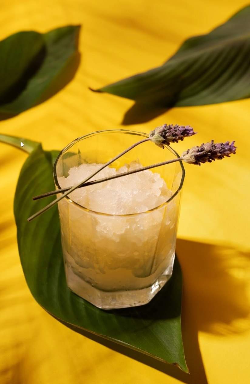 Frozen cocktail with lavender and leaves on a yellow backdrop