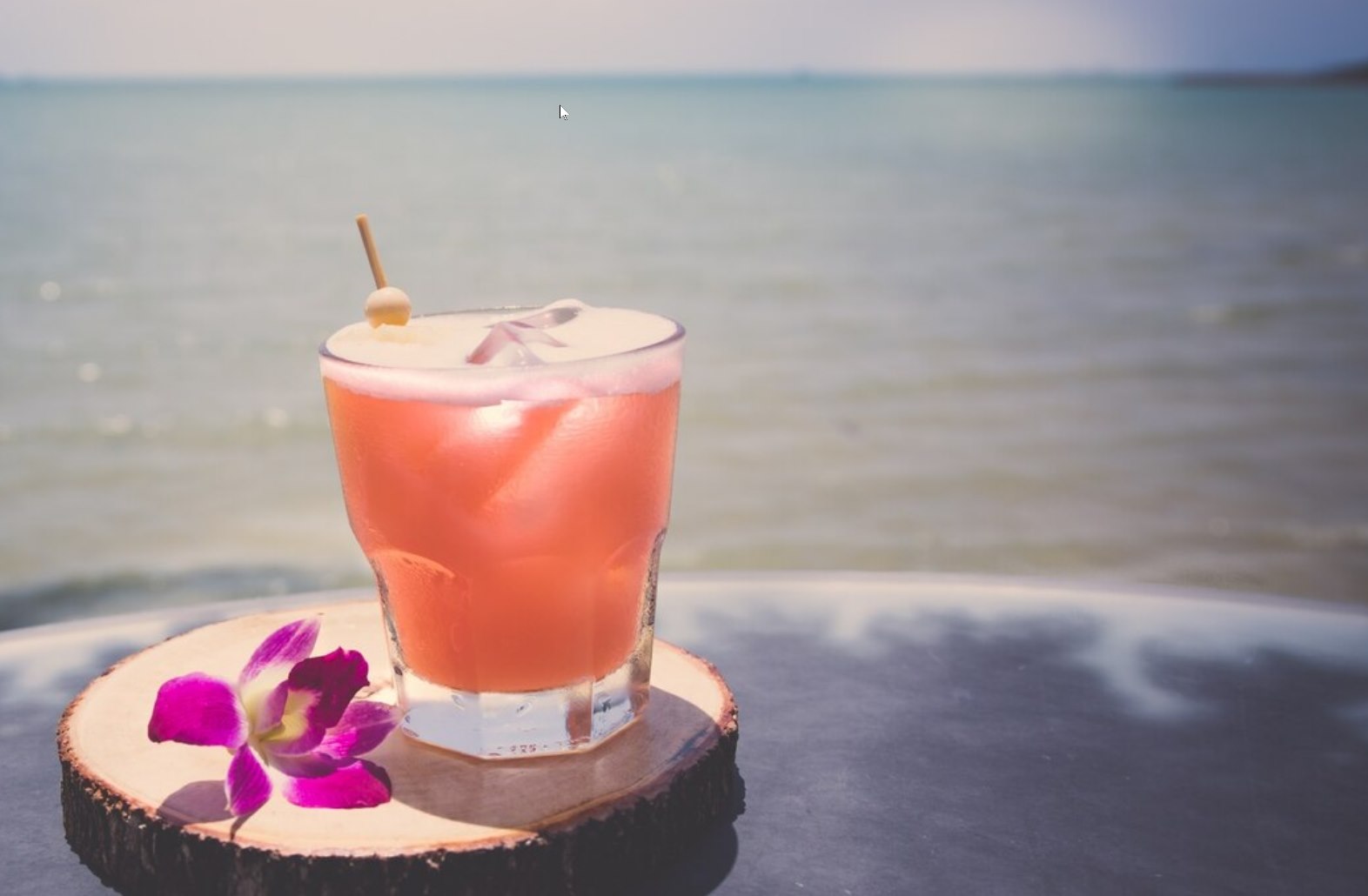 A pink RockaRita cocktail served beside the ocean